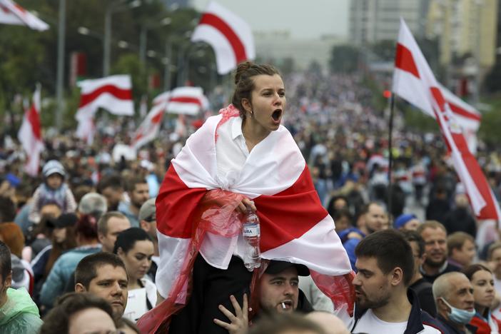 A woman covered in a red and white flag is among protesters in Minsk on Sept. 6. Sunday's demonstration marked the beginning of the fifth week of daily protests calling for Belarusian President Alexander Lukashenko's resignation.
