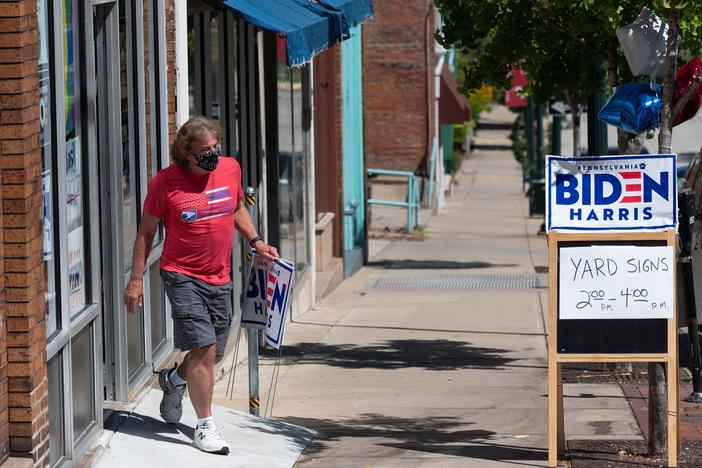 A man walks out of the Washington County Democratic Party office last week, in the suburbs of Pittsburgh, after taking a Joe Biden yard sign. Because of the coronavirus pandemic, Biden's campaign isn't doing any in-person door-knocking.
