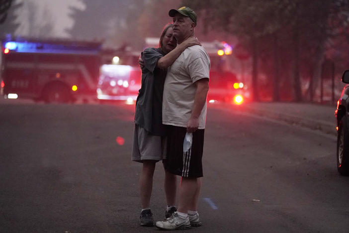 A couple embrace Thursday while touring an area devastated by the Almeda Fire in Phoenix, Ore.