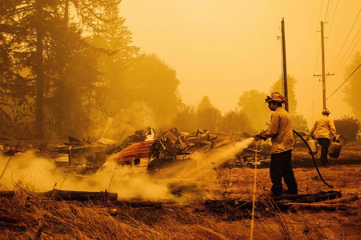 Oregon firefighters put out embers in Mill City, Ore., on Sept. 10, 2020, as they battle the Santiam Fire. As fires ravage the Pacific Northwest, fear and rumors have taken hold on social media.