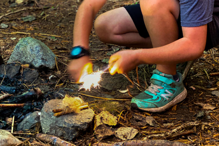 Asher Wool, 8, uses a ferro rod and striker to light a bundle of tinder aflame at Earthwork school in western Massachusetts.