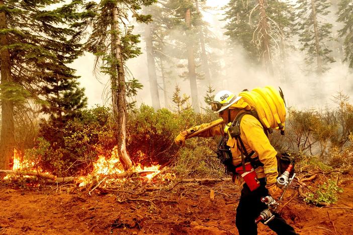 Cal Fire Battalion Chief Craig Newell carries hose while battling the North Complex Fire in Plumas National Forest, Calif., on Monday.