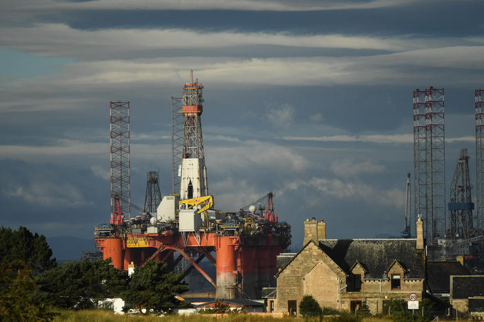 An oil rig towers over houses last week in Nigg, Scotland. Major players in the oil industry expect depressed oil demand and low prices to continue well into next year.