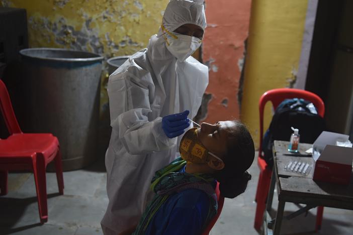 A health worker wearing protective gear collects a swab sample during a medical screening for the coronavirus in Mumbai on Wednesday. The number of registered coronavirus cases passed 5 million on Wednesday.