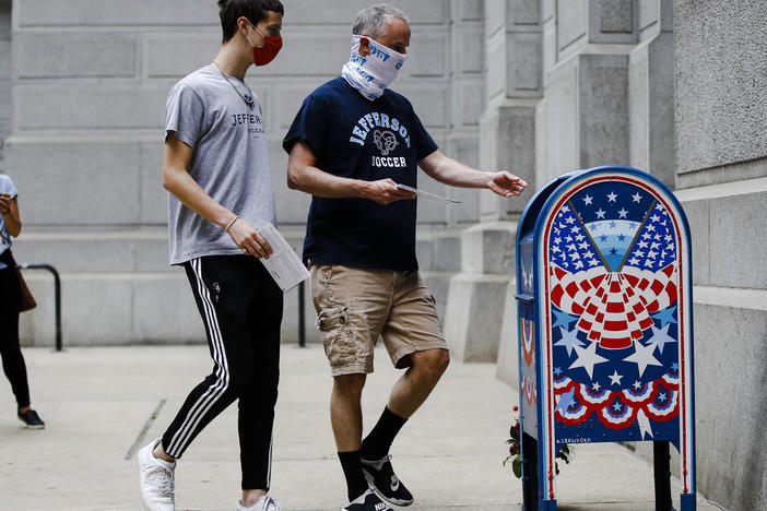 Benjamin Graff, center, and his son Jacob Graff, 19, drop off their mail-in ballots for the Pennsylvania primary election, in Philadelphia, on June 2, 2020. The state Supreme Court affirmed Thursday that counties may use drop boxes for voters casting mail-in ballots.