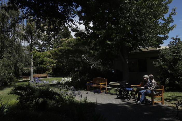 Larry Yarbroff visits his wife Mary at Chaparral House in Berkeley, Calif. in July. California health authorities had allowed some visits to resume, and now federal regulators are doing the same, with measures to try to block the spread of the coronavirus.