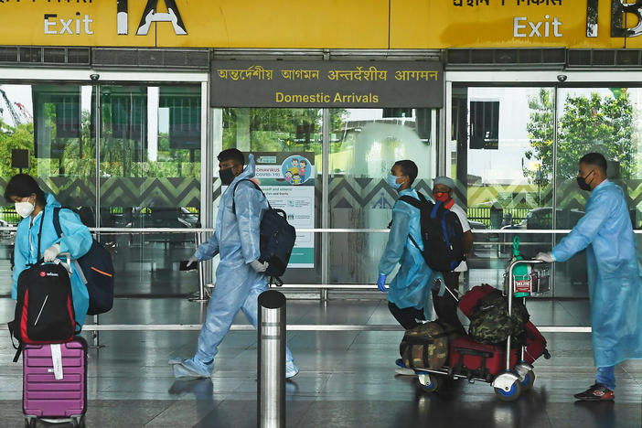 Air passengers wearing practically full-body coveralls at the Netaji Subhas Chandra Bose International Airport in India.