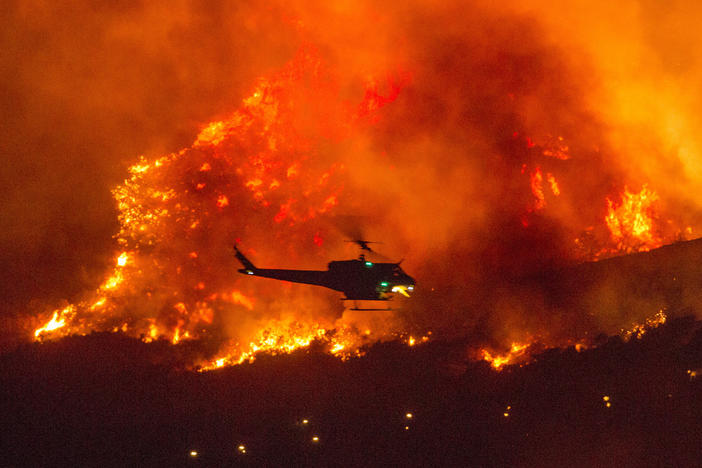 A helicopter prepares to drop water at a wildfire in Yucaipa, Calif., on Sept. 5. A firefighter was killed in the El Dorado blaze on Thursday.