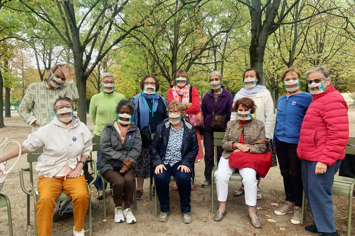 Suzy Margueron (seated, center) who advocates for people with hearing loss, likes to gather with friends in Paris' Luxembourg Gardens. All have transparent masks, but say it's others who should be wearing them too.