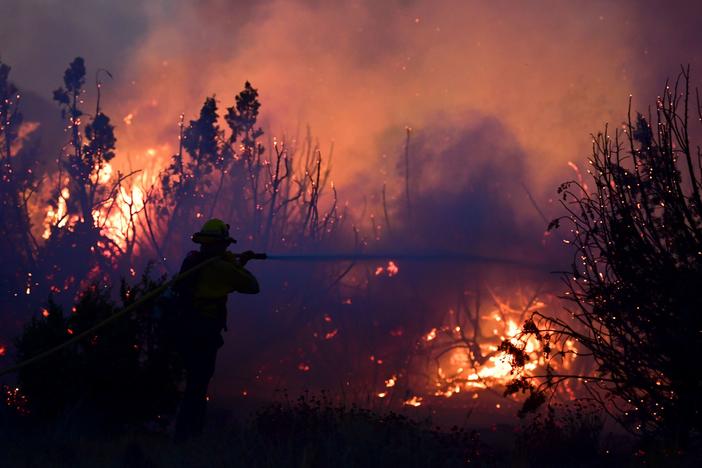 A firefighter works to put out flames of the Bobcat Fire in Juniper Hills, Calif. As of Sunday, the wildfire has grown to more than 99,000 acres and is 15% contained.