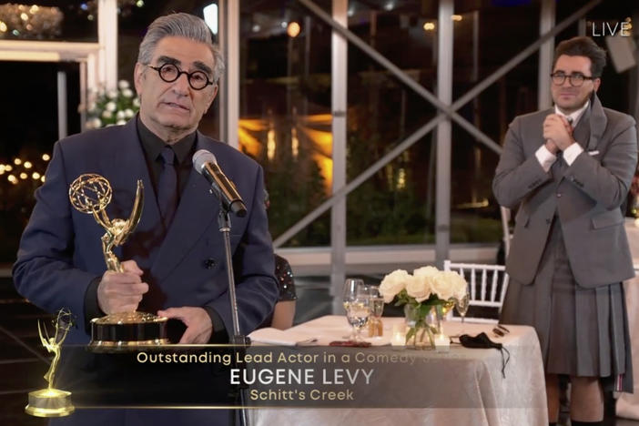 Eugene Levy accepts his award for lead actor in a comedy series for <em>Schitt's Creek </em>as his son (and creative partner) Dan Levy looks on at Sunday night's Emmy Awards.