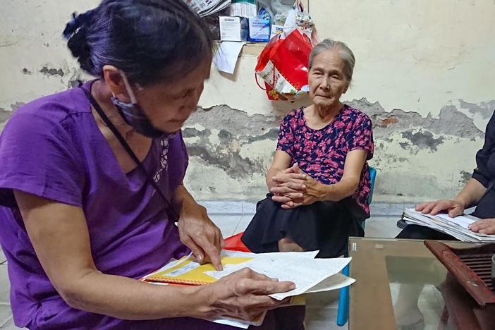 Dao Thi Hoa, right, chairwoman of the Intergenerational Self Help Club in the Khuong Din ward of Hanoi in Vietnam, checks the club's account book with other members.