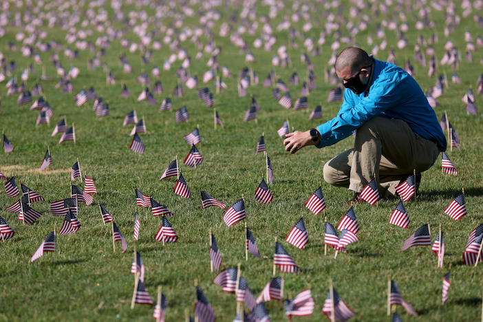 The U.S. hit a tragic milestone Tuesday, recording more than 200,000 coronavirus deaths. Here, Chris Duncan, whose 75-year-old mother, Constance, died from COVID-19 on her birthday, visits a COVID Memorial Project installation of 20,000 U.S. flags on the National Mall. The flags are on the grounds of the Washington Monument, facing the White House.