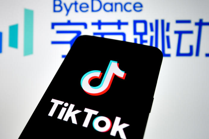 In this photo illustration, a TikTok logo seen displayed on a smartphone with a ByteDance logo picture in the background.