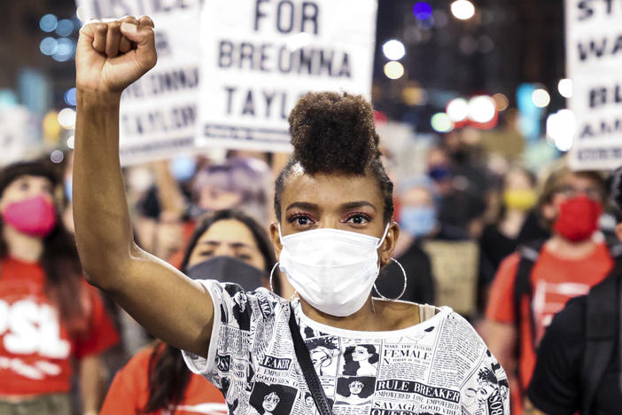 Sheree Barbour holds her fist in the air in Denver, Colo. as people protest the grand jury decision in the Breonna Taylor case.