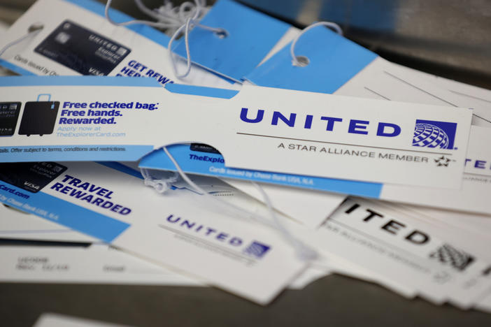 United Airlines baggage tags are displayed on a table at San Francisco International Airport. The carrier says it's starting a pilot program next month that will offer rapid coronavirus testing at the airport or via a self-collected, mail-in test ahead of a flight.