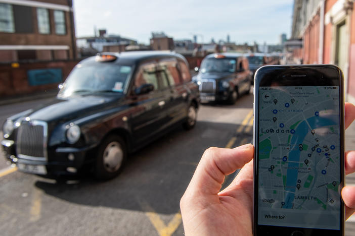 A phone shows the Uber app in front of a taxi stand at Waterloo station in London on Monday. The ride-sharing service won its appeal after Transport for London denied a renewal of its operating license late last year.