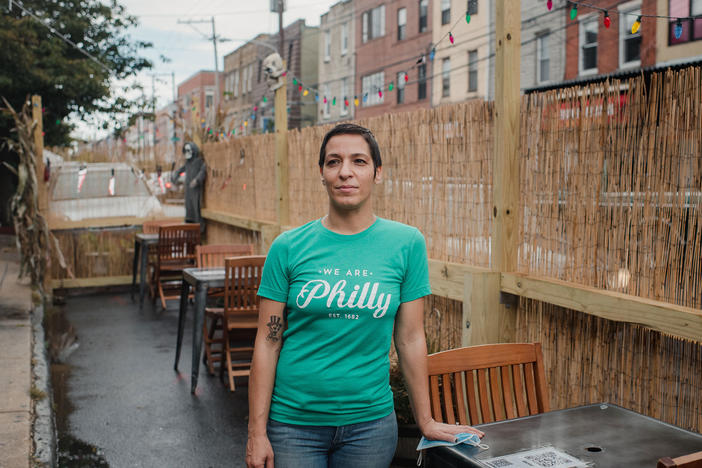 Danielle Renzulli, owner of 12 Steps Down Bar in Philadelphia, poses by the tables she has set up in what used to be parking spots. She was expecting some negative reactions from neighbors, given how valuable parking is in the area, but to her surprise, she received no complaints.