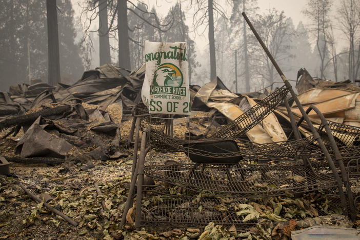 A sign for a recent graduate is bent but not burned in Blue River, Ore., eight days after the Holiday Farm Fire swept through its business district.