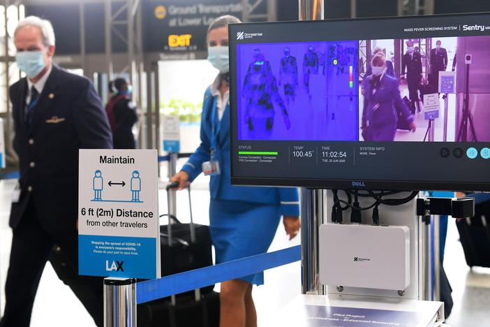 Flight crew members walk past thermal cameras that check passengers' body temperatures at Los Angeles International Airport on June 23. As businesses look to reopen, technology firms are offering an array of monitoring systems to try to control the coronavirus.