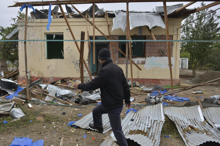 A man walks past a house destroyed by shelling during fighting over Nagorno-Karabakh in Agdam, Azerbaijan, on Oct. 1. The International Committee of the Red Cross says civilian deaths and injuries have been reported.