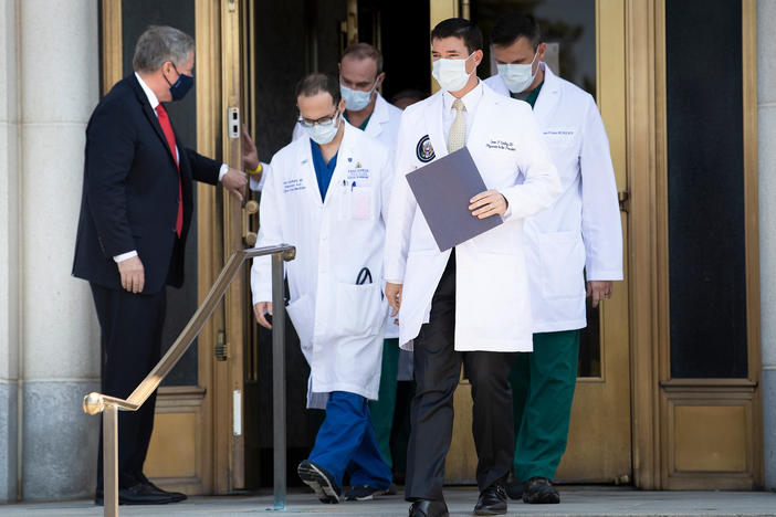 White House chief of staff Mark Meadows holds the door for White House physician Dr. Sean Conley (center) and other members of the president's medical team ahead of a briefing for reporters on Sunday.