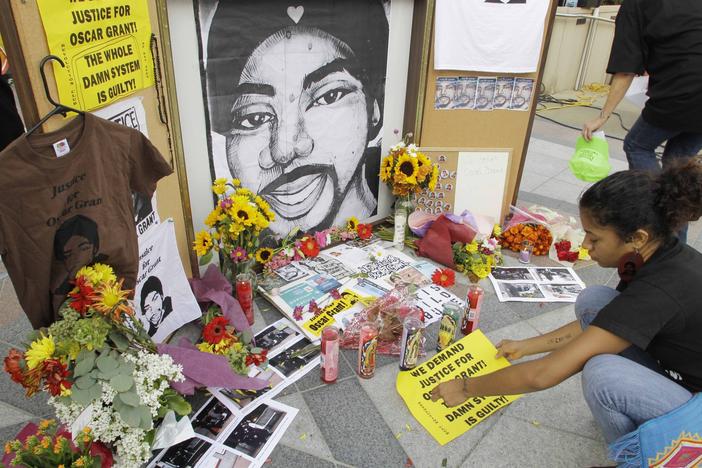 A woman leaves a sign at a street-side memorial to shooting victim Oscar Grant in Oakland, Calif., in 2010. A Northern California prosecutor announced Monday that she will reopen the investigation into the killing of Grant at a train station by a police officer 11 years ago.