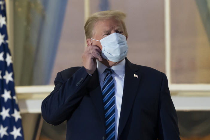 President Trump removes his mask upon returning to the White House on Monday after undergoing treatment for COVID-19 at Walter Reed National Military Medical Center in Bethesda, Md.