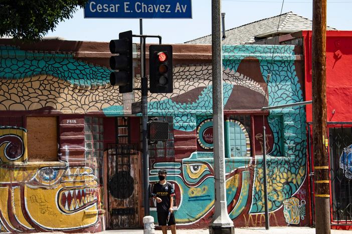 A man waits to cross the street in the largely Latino neighborhood of East Los Angeles on Aug. 7. California has implemented a new health equity metric to help address the outsize effect of coronavirus on the state's communities of color.