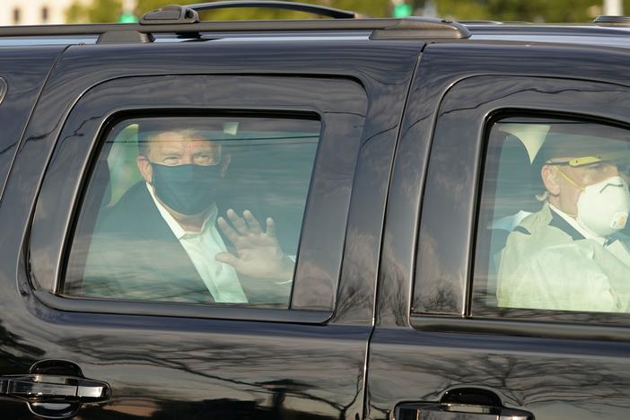 President Trump waves from a motorcade outside Walter Reed Medical Center, accompanied by Secret Service agents on Sunday.