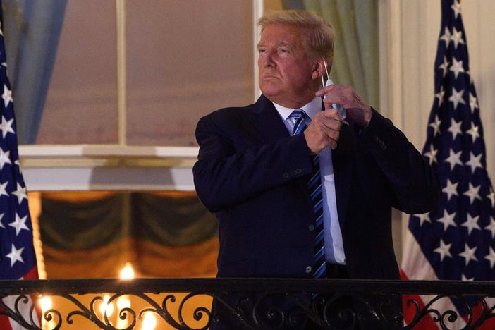 President Trump takes off his face mask Monday night as he arrives at the White House upon his return from Walter Reed National Military Medical Center.