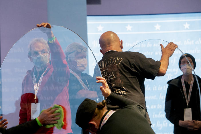 Workers clean plexiglass dividers installed at the University of Utah in preparation for the debate between Sen. Kamala Harris and Vice President Pence.