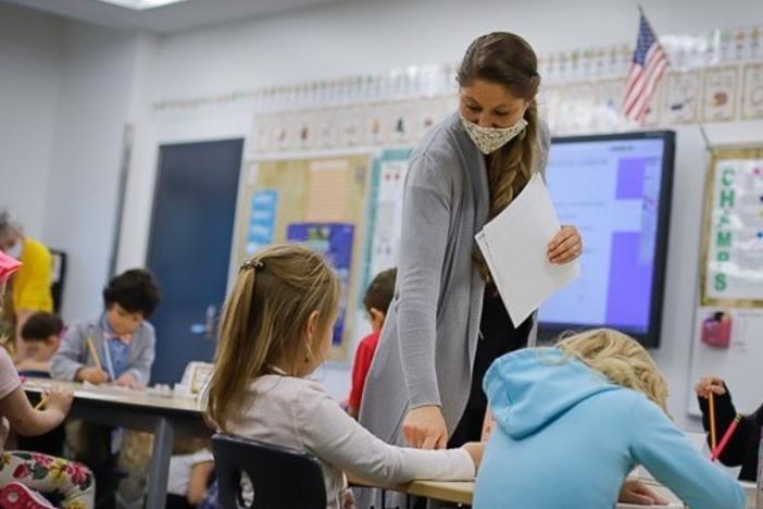 Public school teacher Kelly Mrozik holds in-person class for first graders in Wasilla, Alaska. She is required to wear a mask. Her students are not.