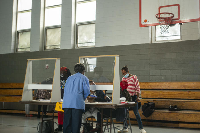 Poll workers sit behind plexiglass barriers during primary elections on June 2 in Philadelphia. Many cities are reporting a surge of volunteers to work the polls although Philadelphia still faces a shortage ahead of next month's election.