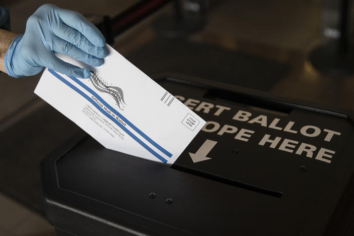 In this May 2020 photo, a voter casts her mail-in ballot at in a drop box in West Chester, Pa., prior to the primary election. On Saturday a federal judge blocked a Trump campaign lawsuit to limit the use of drop boxes in the state.