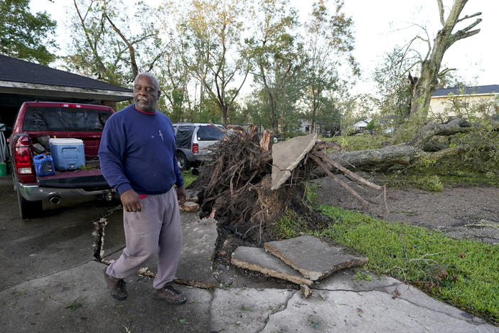 Marcus Peterson walks past a downed tree in his yard in Jennings, La., after Hurricane Delta moved through the region. Delta hit as a Category 2 hurricane with top winds of 100 mph before rapidly weakening over land.