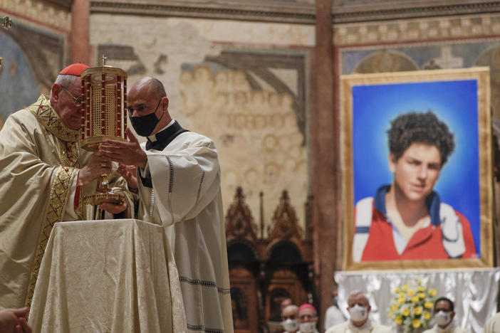 Cardinal Agostino Vallini, left, holds a relic of 15-year-old Carlo Acutis, an Italian boy who died in 2006 of leukemia, during his beatification ceremony celebrated in the St. Francis Basilica, in Assisi, Italy, on Saturday.