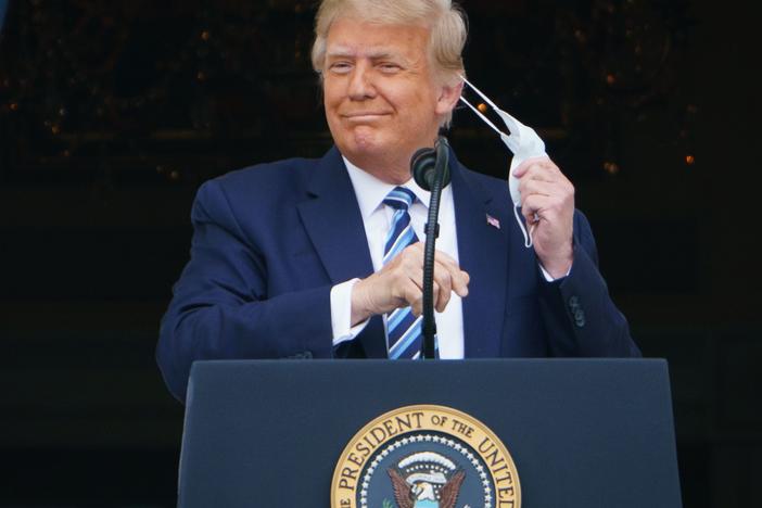 President Trump takes his mask off before speaking from the South Portico of the White House during a rally on Saturday. He is traveling for another rally for the first time on Monday.