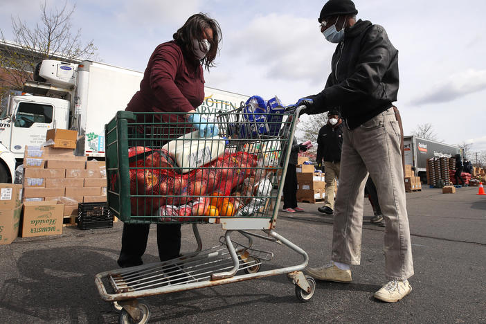 A volunteer loads food into a cart at a mobile pantry in Detroit in April 2020. The COVID-19 pandemic has led to an uptick in the demand at food banks.