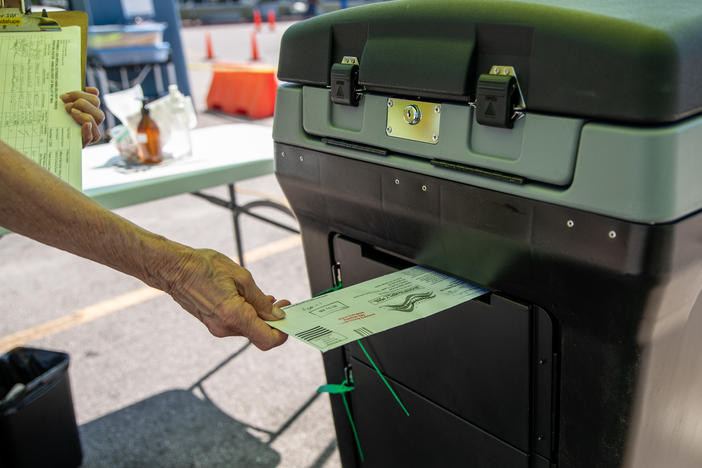 A federal appeals court is allowing Texas Gov. Greg Abbott's limit of one absentee ballot drop-off spot per county to stand, saying voters have many options. Here, a worker puts a ballot into a lockbox at a drive-through mail ballot hand delivery center in Austin.
