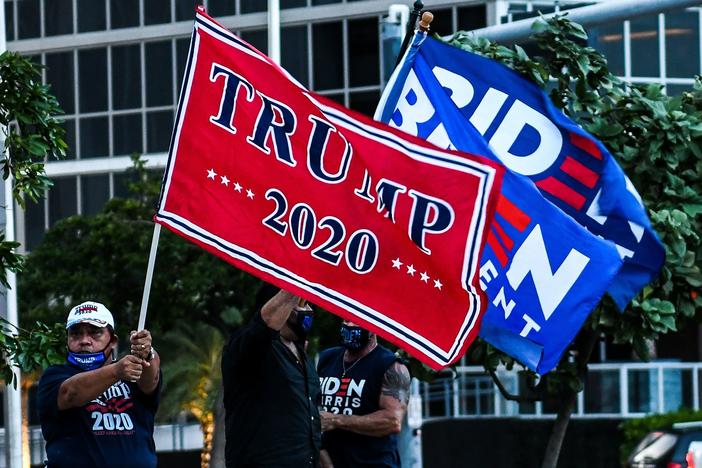 Supporters of President Trump and Democratic presidential nominee Joe Biden wave flags prior to Biden's arrival for a town hall in Miami.