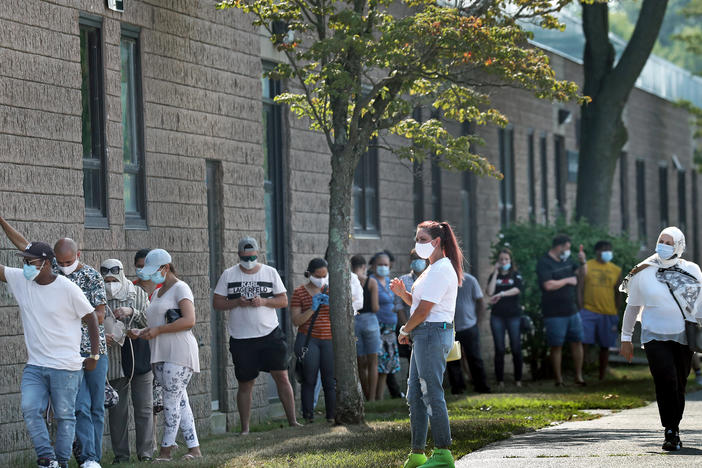 People wait in the shade while in line to get coronavirus tests in Revere, Mass.