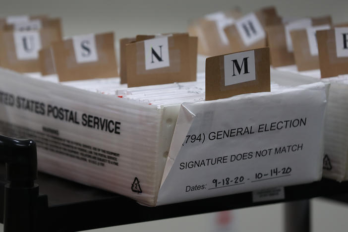 Mail-in ballots that need to be reviewed because of signature discrepancies sit in boxes at the Miami-Dade County Elections Department in Doral, Fla., on Oct. 15. Signature problems are a frequent reason that ballots are rejected, though many states allow voters to fix those problems before Election Day.