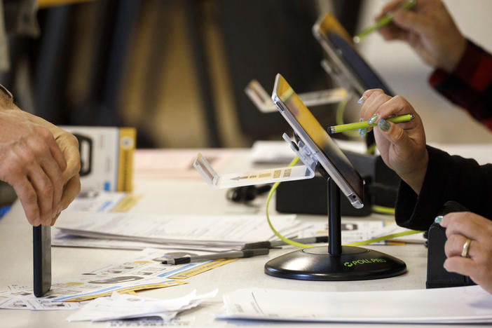 An election worker uses an electronic pollbook to check voters at a polling station in the Echo Park Recreation Complex in Los Angeles on March 3, 2020.