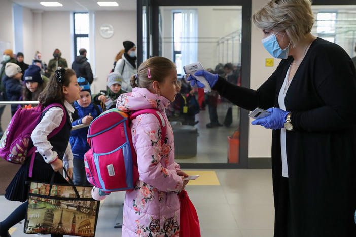 More than 40 million coronavirus infections have now been reported worldwide. Here, a staff member at a school in Moscow uses an infrared thermometer on Monday to screen students.
