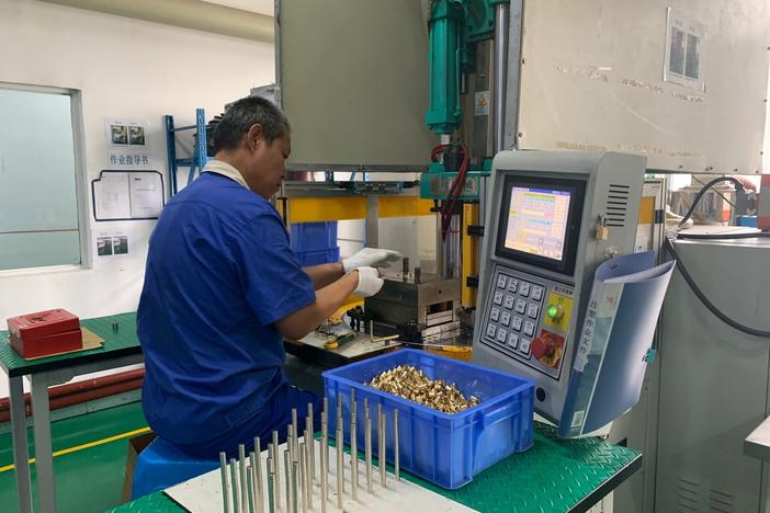 A worker at Thinova Magnet Co. Ltd. puts rare earth magnets into a press at a factory in Zhejiang province.