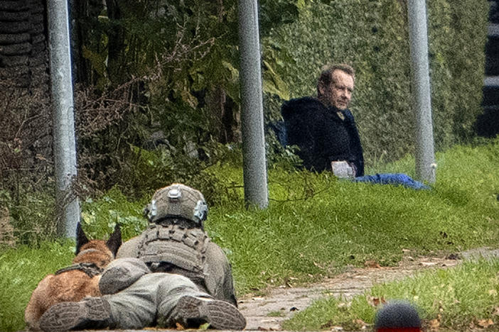 A police marksman and his dog observes convicted killer Peter Madsen threatening police with detonating a bomb while attempting to break out of jail Tuesday in Albertslund, Denmark.