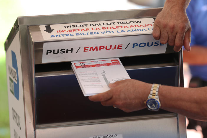 A poll worker places vote-by mail ballots into a ballot box this month at the Miami-Dade County Election Department headquarters in Doral, Fla. Voters in Florida are among those who have reported receiving emails threatening them to vote for President Trump.