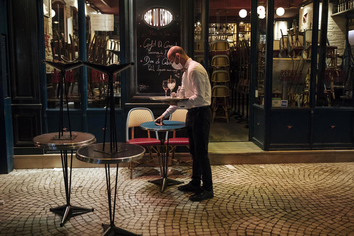 A waiter closes a bar terrace in Paris earlier this month amid a surge in coronavirus cases.