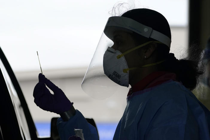 A University of Washington research coordinator holds up a swab after testing a someone for coronavirus on Oct. 23 in Seattle. The U.S. recorded a record high number of new daily cases Friday.